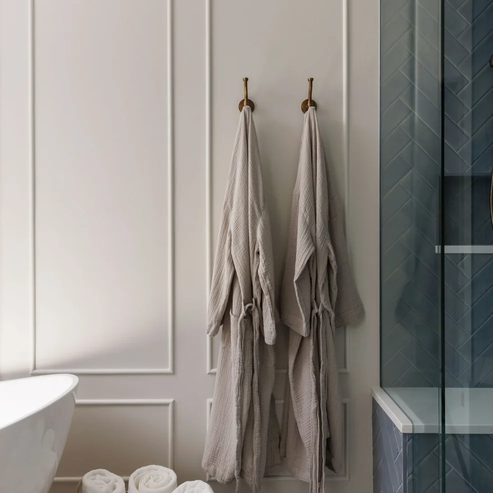 Ensuite panelled wall with aged brass robe hooks beside the herringbone tile shower, 10 Mile Point renovation by Maverick Design, Victoria BC