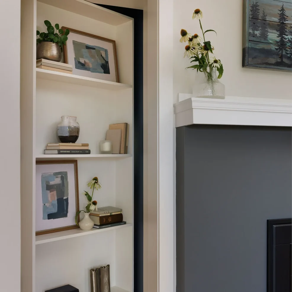 Hidden bookcase door leading to the games room, beside a charcoal fireplace surround, 10 Mile Point renovation by Maverick Design, Victoria BC