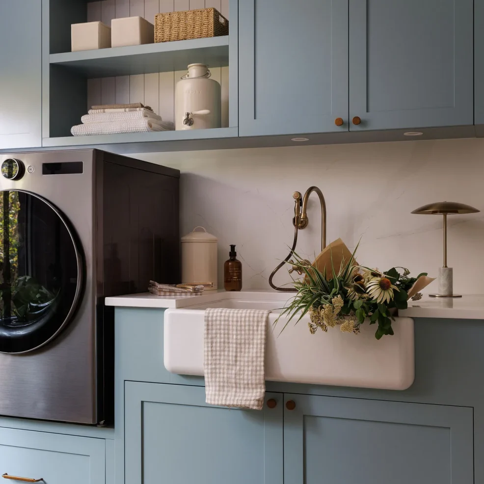 Laundry room with blue Shaker cabinetry, raised front-load washer, farmhouse sink and open shelving, 10 Mile Point renovation by Maverick Design, Victoria BC