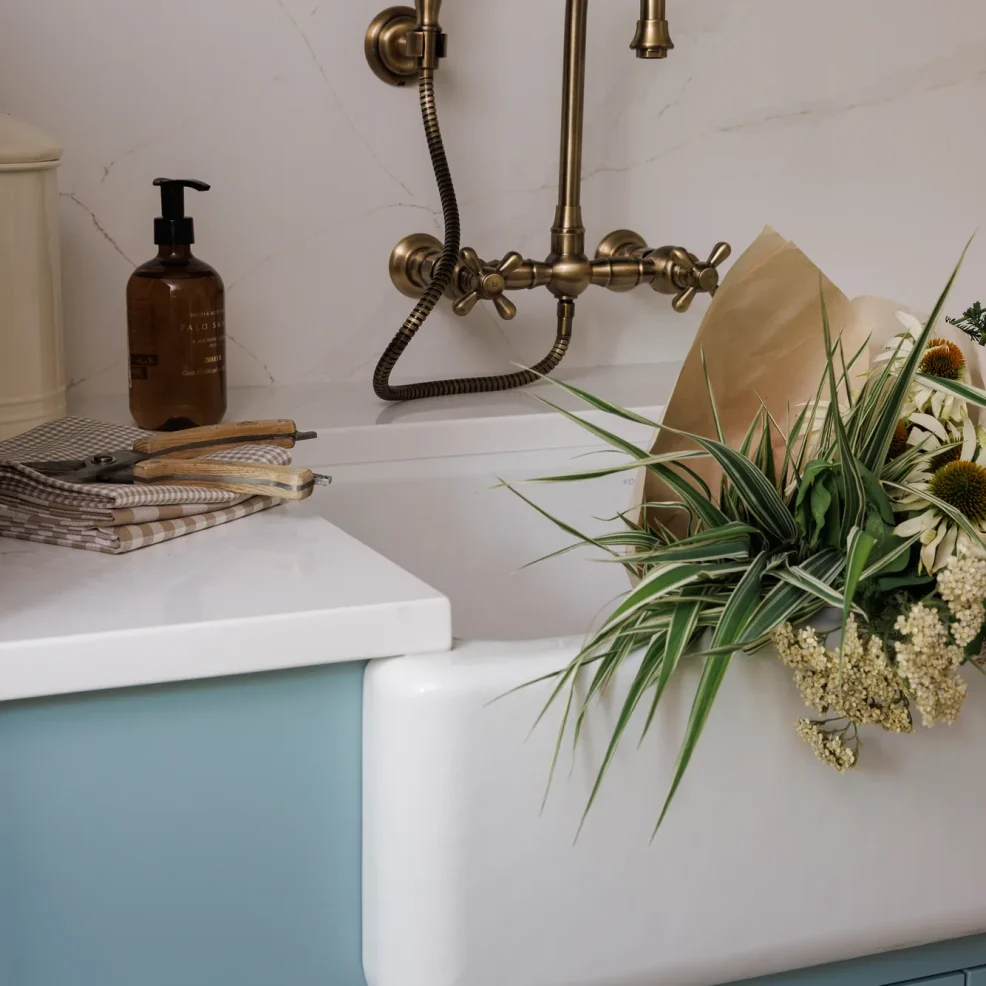Laundry room farmhouse sink with aged brass wall-mounted faucet and sprayer on blue Shaker cabinetry, 10 Mile Point renovation by Maverick Design, Victoria BC
