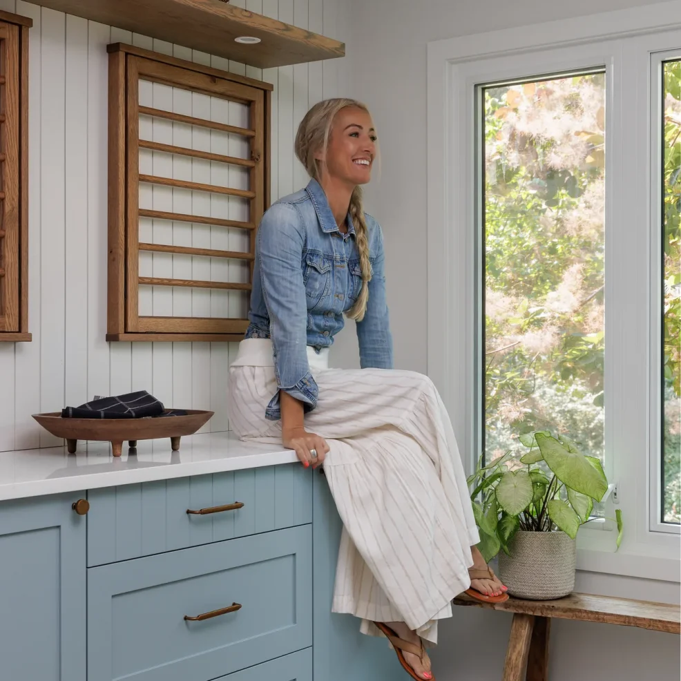 Danielle Keogan in the 10 Mile Point laundry room renovation with blue Shaker cabinetry and oak drying racks, Maverick Design, Victoria BC